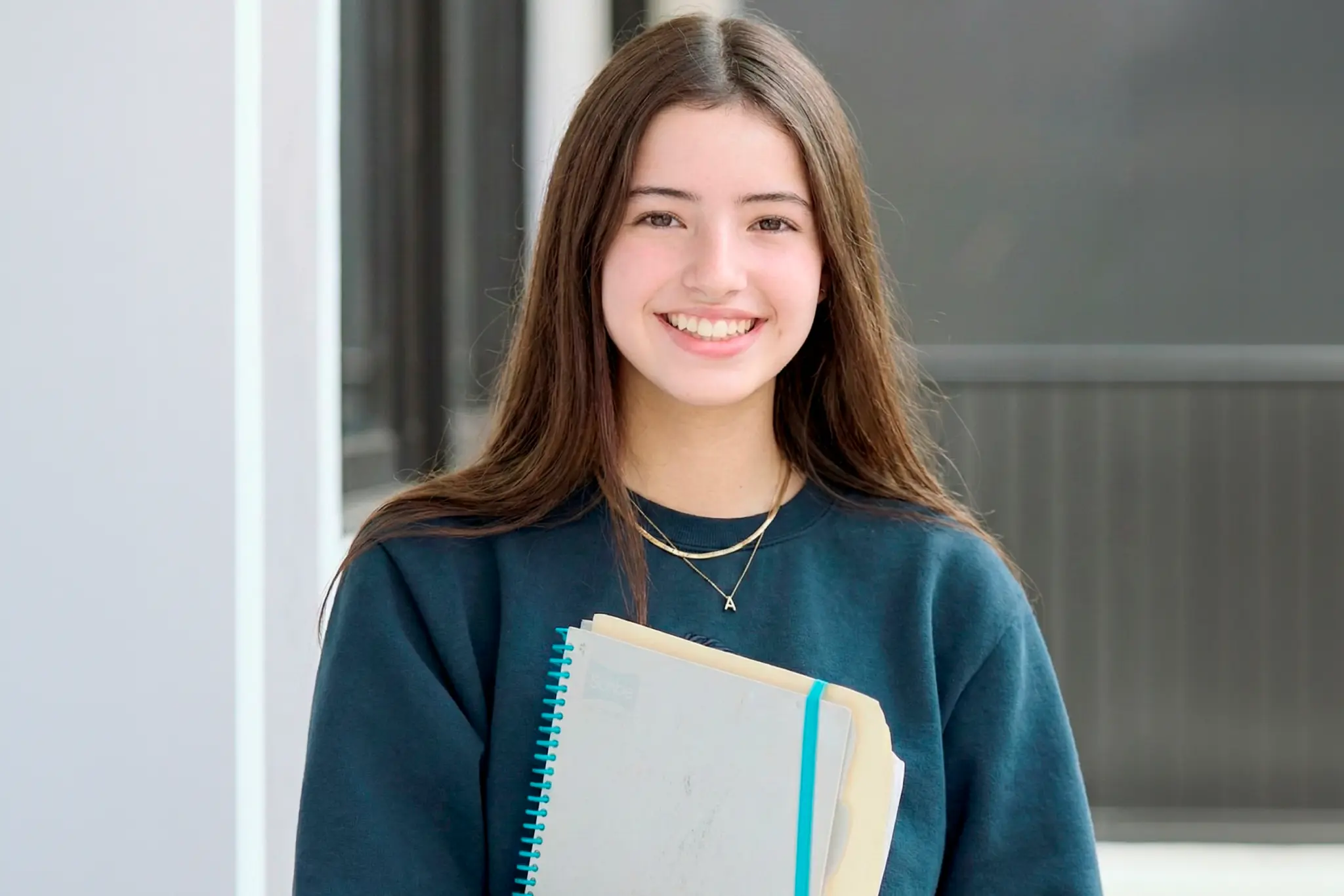 Alumna de high school con cuaderno en las manos.