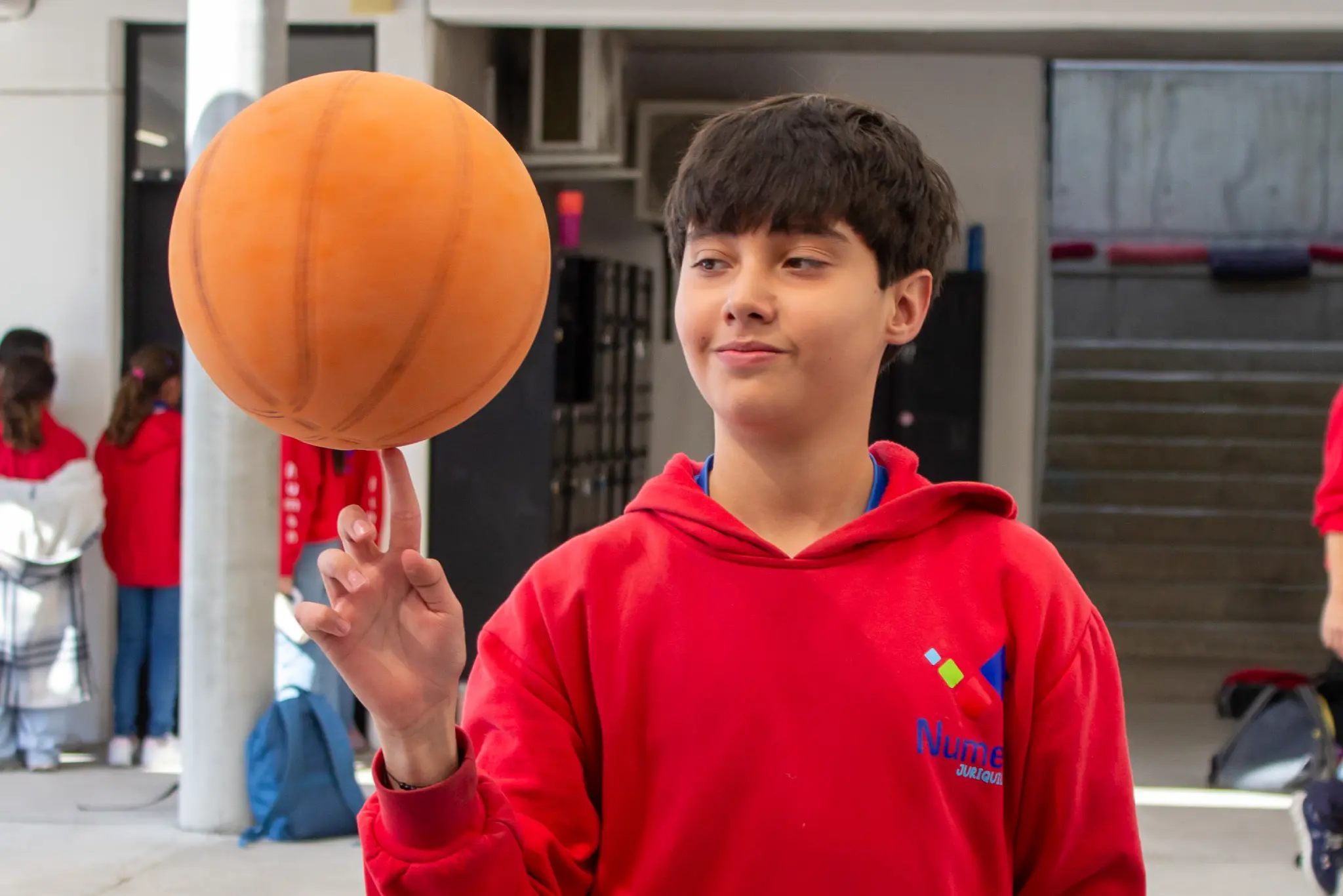 Alumno de middle school con balón de baloncesto durante clase de educación física.